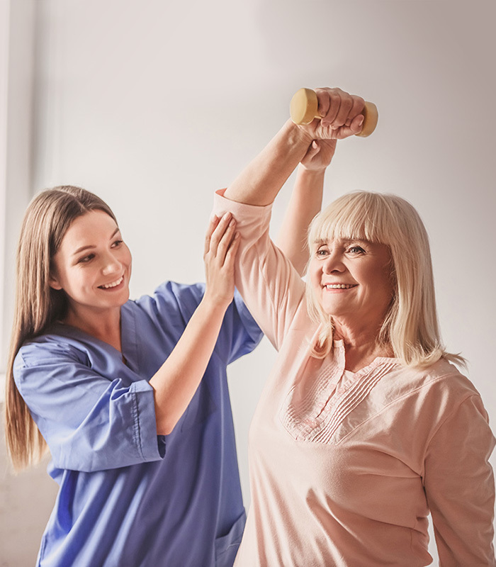 Woman helping older woman lift arm with weight
