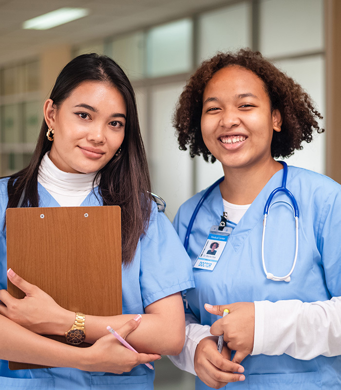 Two female healthcare workers in blue scrubs